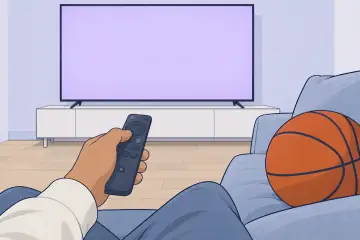 テレビのリモコンを持つ手とソファの上のバスケットボール